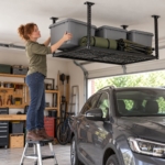 Woman on a step stool sliding a storage box onto the overhead ceiling rack