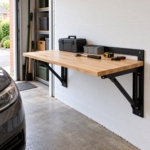 Wall-mounted folding workbench unfolded beside a parked car in a narrow garage